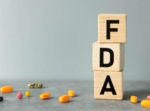 Children's blocks stacked to spell FDA with pills surrounding them