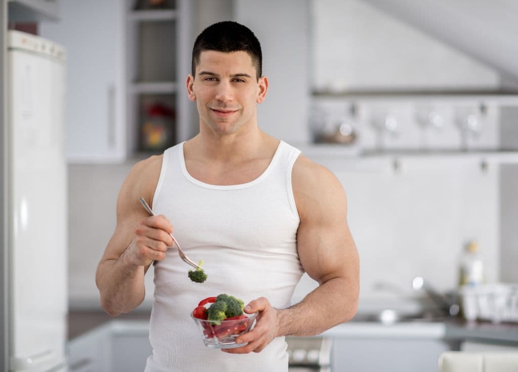 A man looking at the camera while eating strawberries