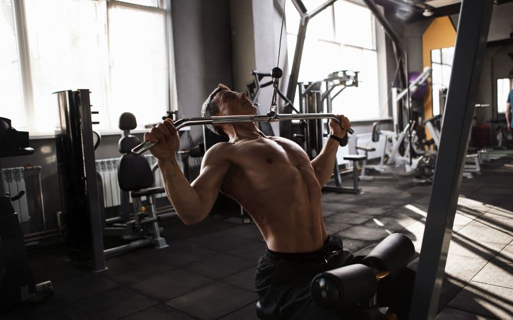 A man using a pull down machine in the gym