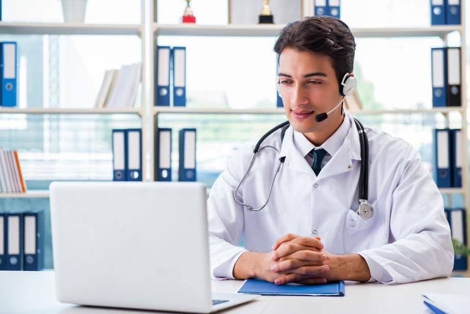 A male doctor looking at his computer, conducting a telemedicine call