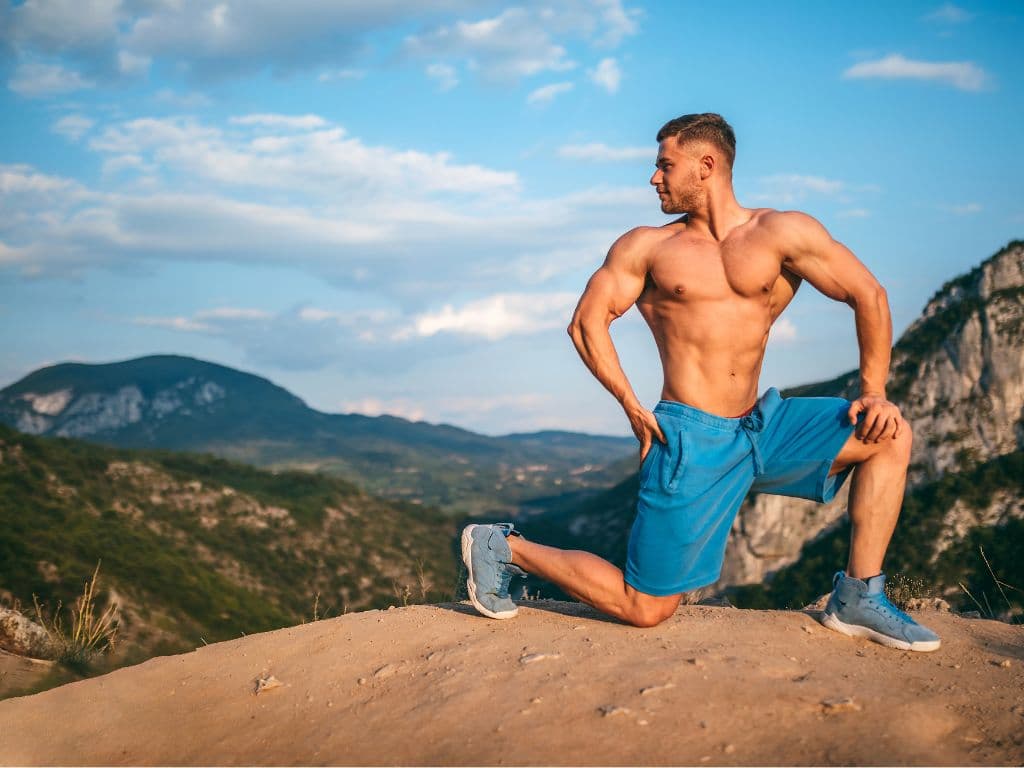 A shirtless man posing in front of a beautiful landscape
