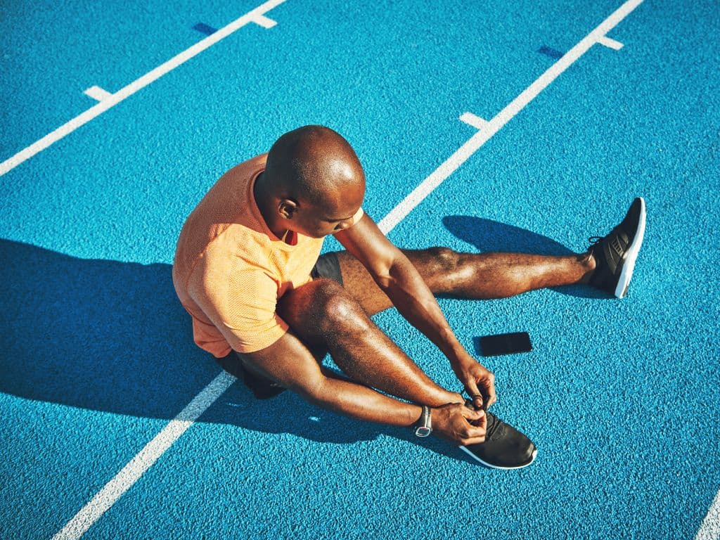 A man tying his shoes on the race track