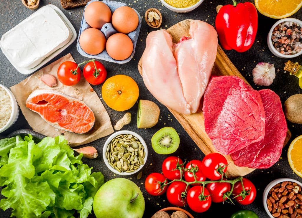 A charcuterie spread with eggs tomatoes, meats, apples, cheese, pepper, and more.