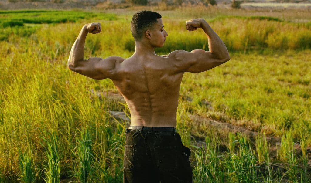 A man flexing while facing an open field