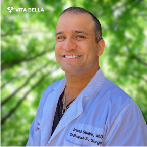 Dr. Irshad Shakir smiling at the camera in his doctor scrubs