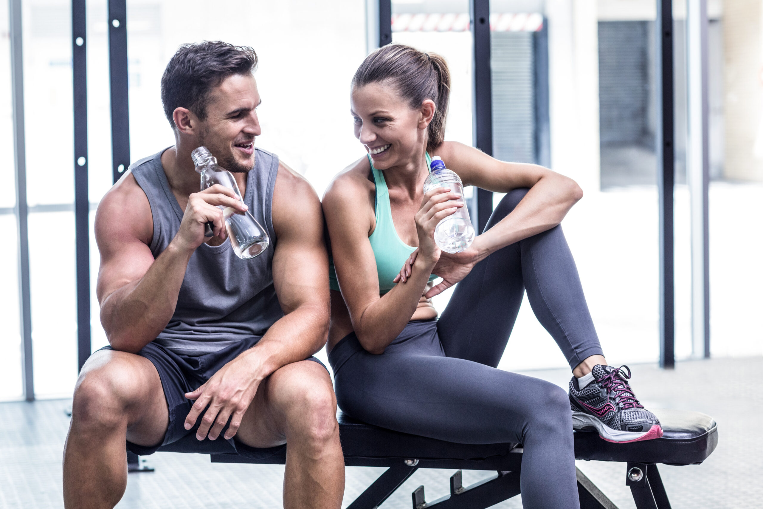 two people resting drinking water after a workout